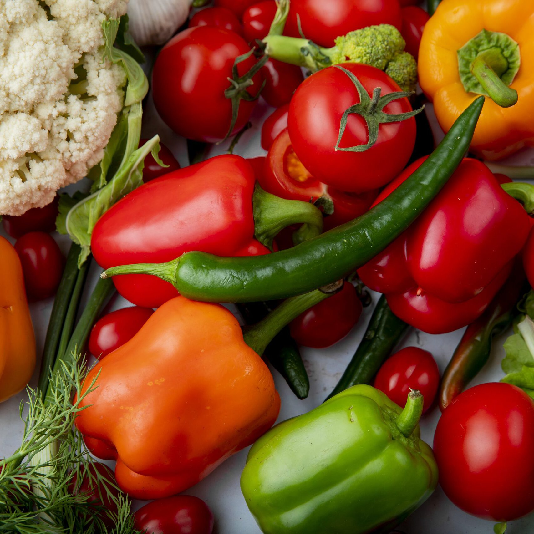 top view of fresh ripe vegetables tomatoes green chili pepper colorful bell peppers garlic broccoli and cauliflower on marble background